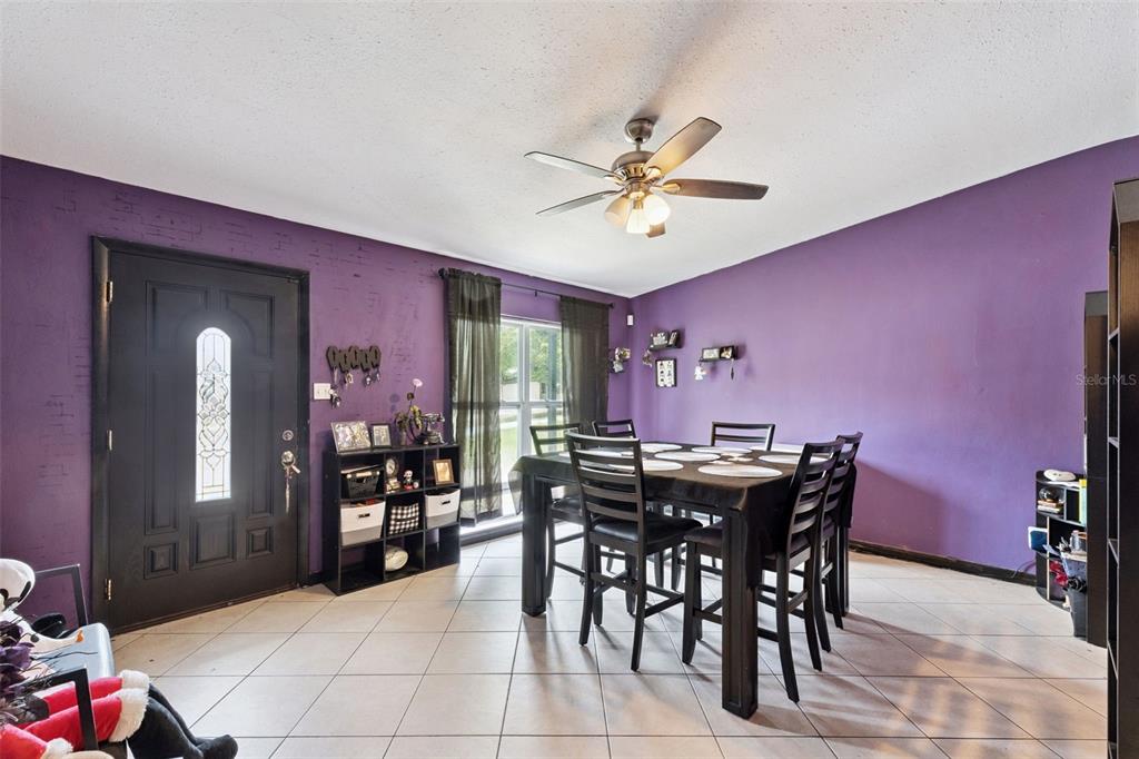 A dining room features purple walls, a dark wood table with chairs, and tiled floors — 6204 OAKCREST CIRCLE, ORLANDO, FL