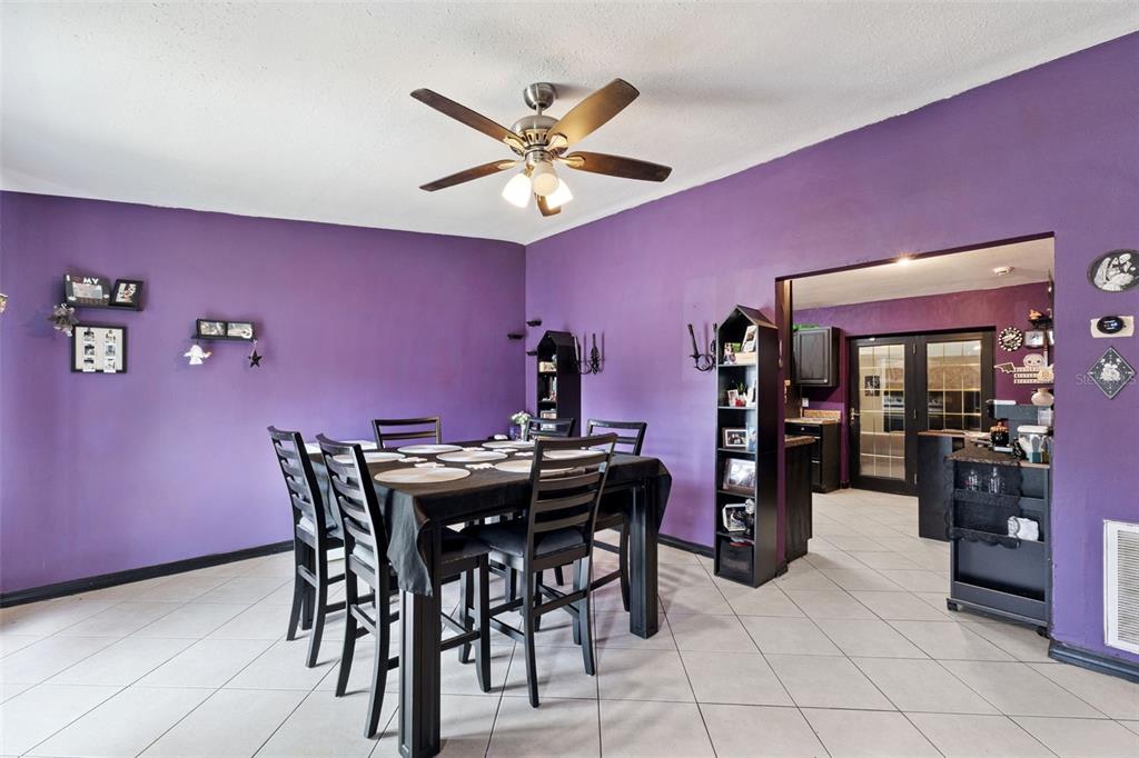 A dining room features purple walls, a dark wood table with chairs, and tile flooring — 6204 OAKCREST CIRCLE, ORLANDO, FL