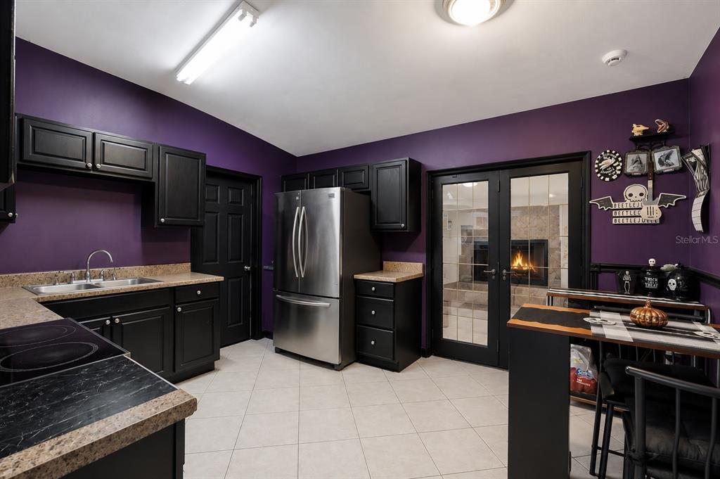 A kitchen features purple walls, black cabinets, stainless steel appliances, and a glass-paned door — 6204 OAKCREST CIRCLE, ORLANDO, FL