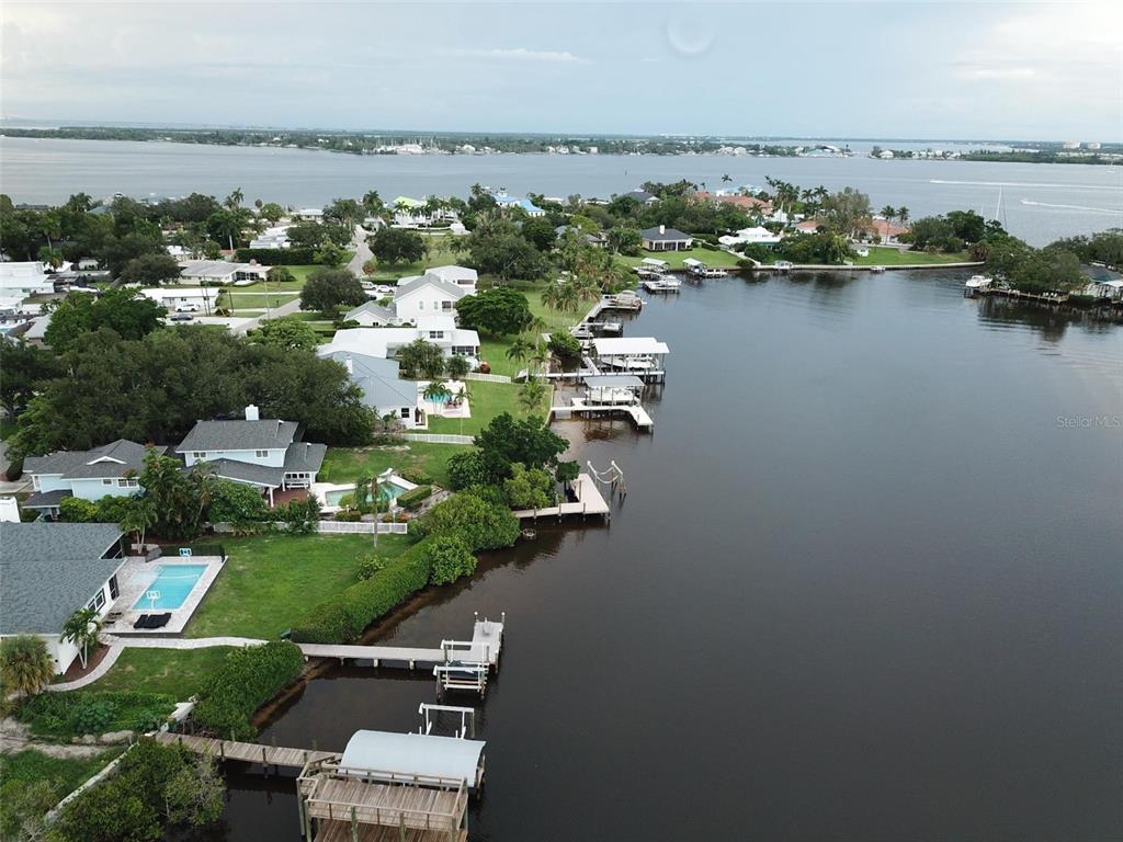 An aerial view shows waterfront homes with private docks along a calm bay — 1211 61ST STREET NW, BRADENTON, FL