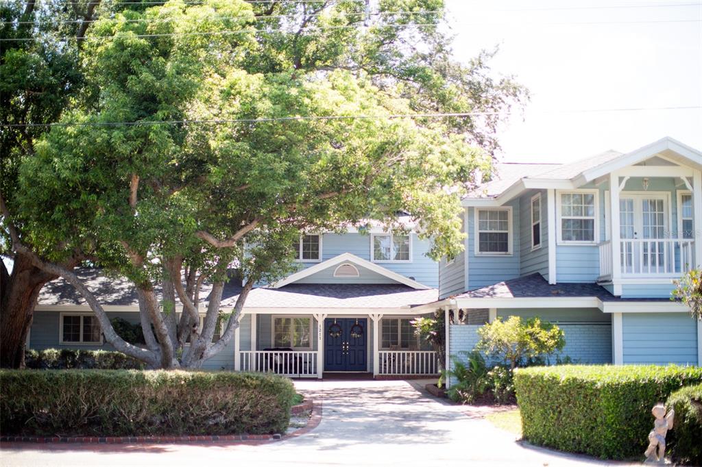 A two-story light blue house with a covered porch, a driveway, and a large tree — 1211 61ST STREET NW, BRADENTON, FL