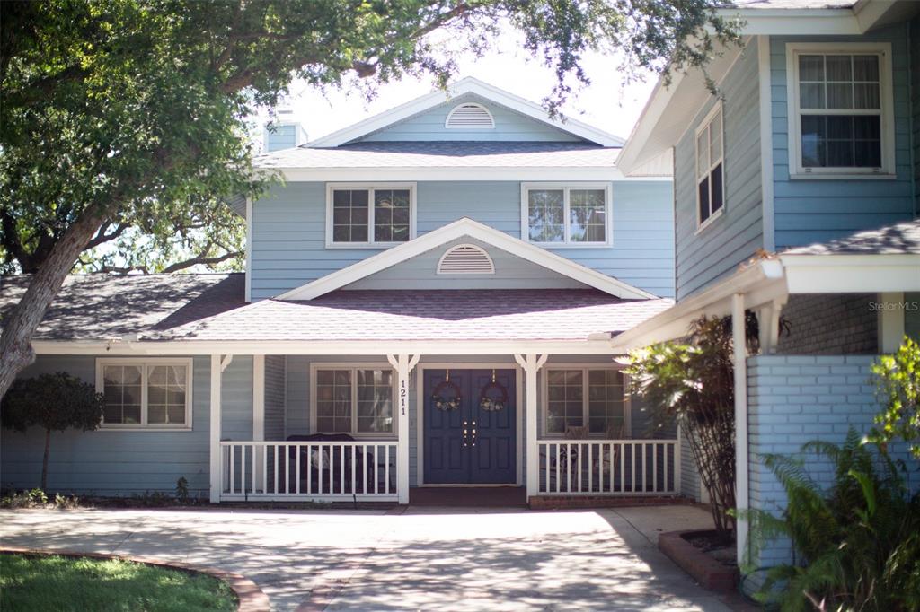 A two-story light blue house with a covered front porch and a paved driveway — 1211 61ST STREET NW, BRADENTON, FL