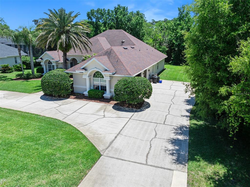 An aerial view shows a single-story house with a large driveway and landscaped front yard — 80 FOXCROFT RUN, ORMOND BEACH, FL