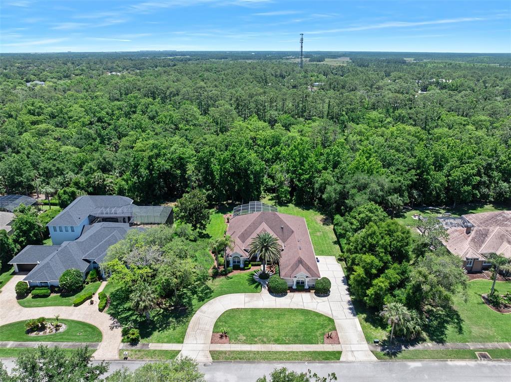 An aerial view shows a suburban house with a circular driveway and a wooded backyard — 80 FOXCROFT RUN, ORMOND BEACH, FL