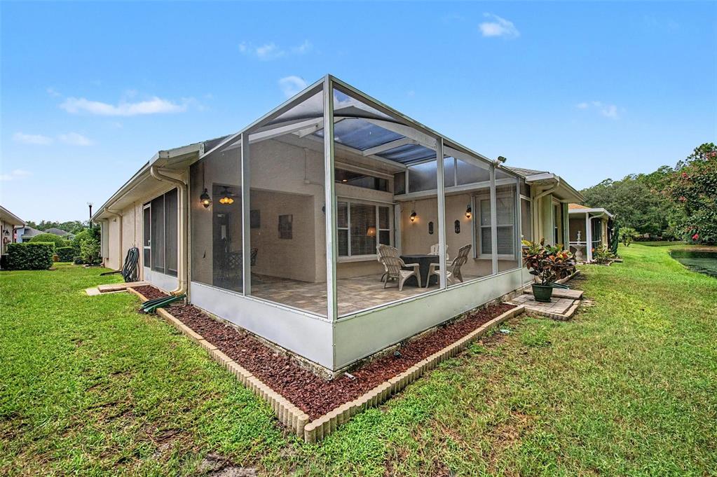 A screened-in patio with tiled flooring sits at the rear of a suburban house — 1808 ORCHARDGROVE AVENUE, NEW PORT RICHEY, FL