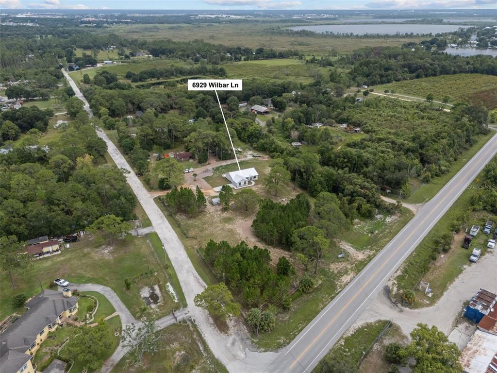 An aerial view shows a white house situated on a large, wooded rural lot — 6929 WILBAR LANE, HAINES CITY, FL