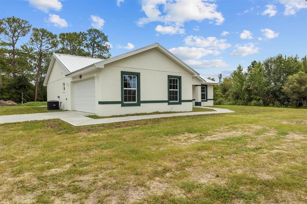 A white single-story house with a metal roof and green trim sits on a grassy lot — 6929 WILBAR LANE, HAINES CITY, FL