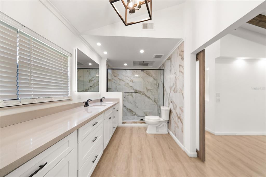 A modern bathroom features a long white vanity, marble-look wall tiles, and a glass-enclosed shower — 19520 168TH STREET, LIVE OAK, FL