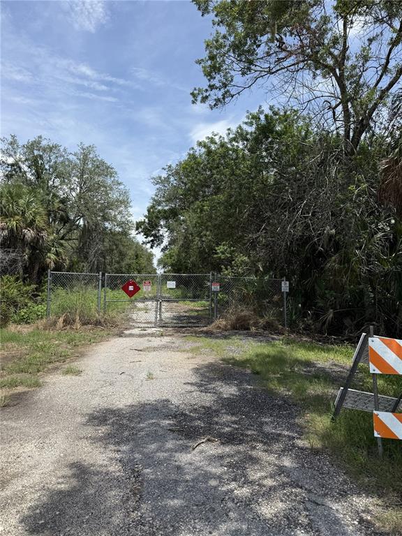 A gravel path leads to a chain-link fence blocking access to a wooded area — 5997 KRACKER AVENUE, GIBSONTON, FL