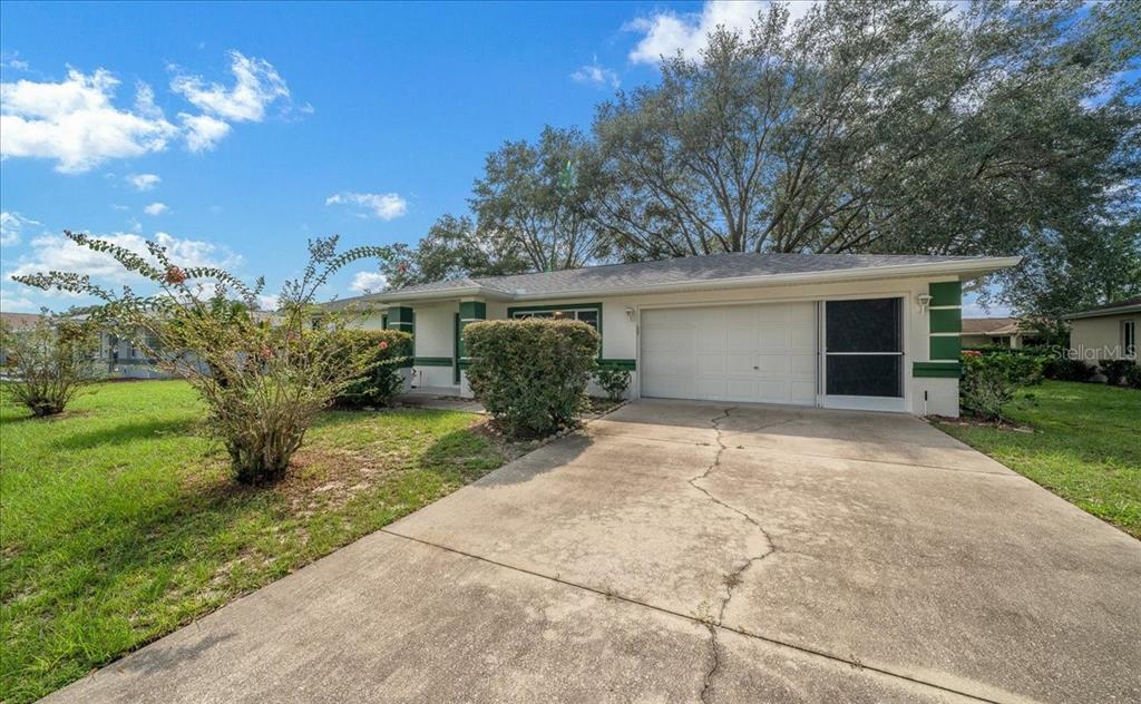A single-story house with a white exterior, green trim, a concrete driveway, and a garage — 9912 SW 61ST COURT, OCALA, FL