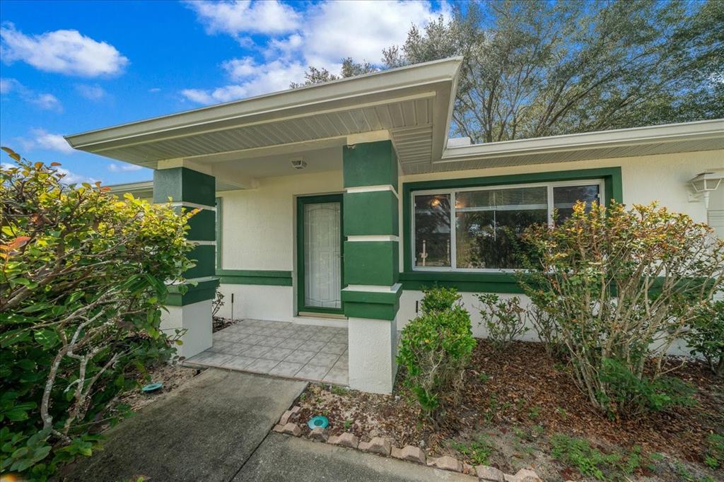 The exterior of a house features a covered porch with green columns and a window — 9912 SW 61ST COURT, OCALA, FL