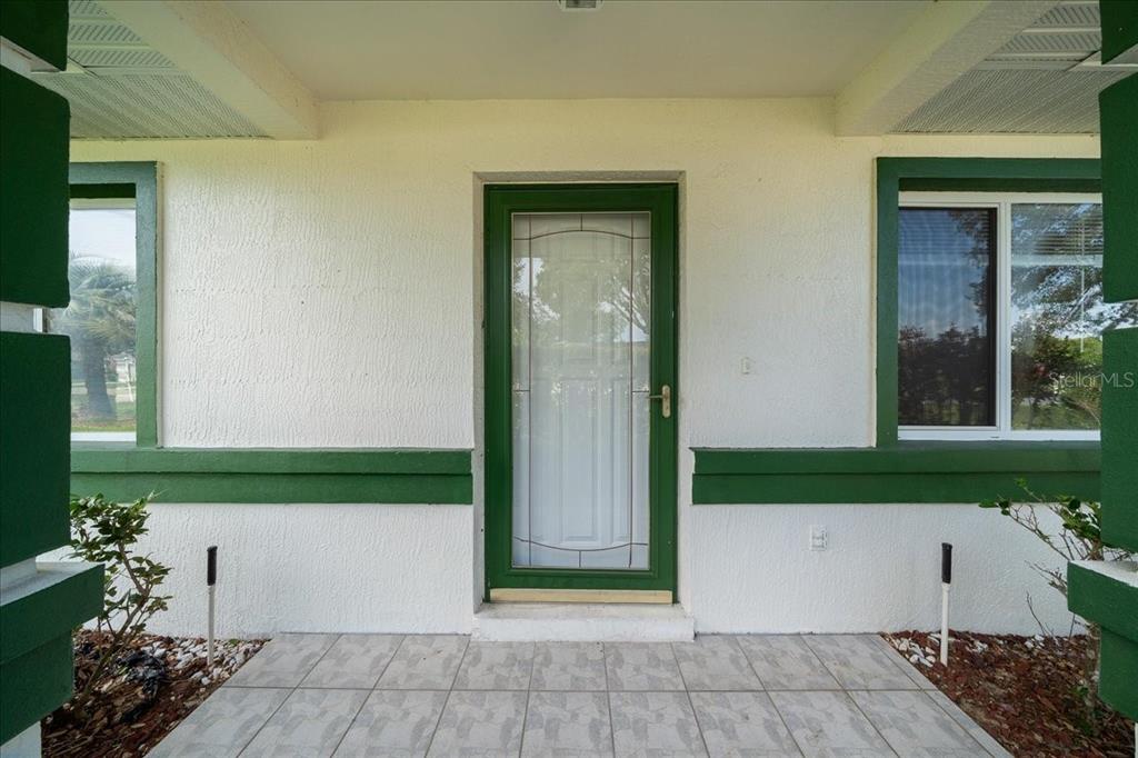A front porch with a tiled floor leads to a green-framed glass storm door — 9912 SW 61ST COURT, OCALA, FL