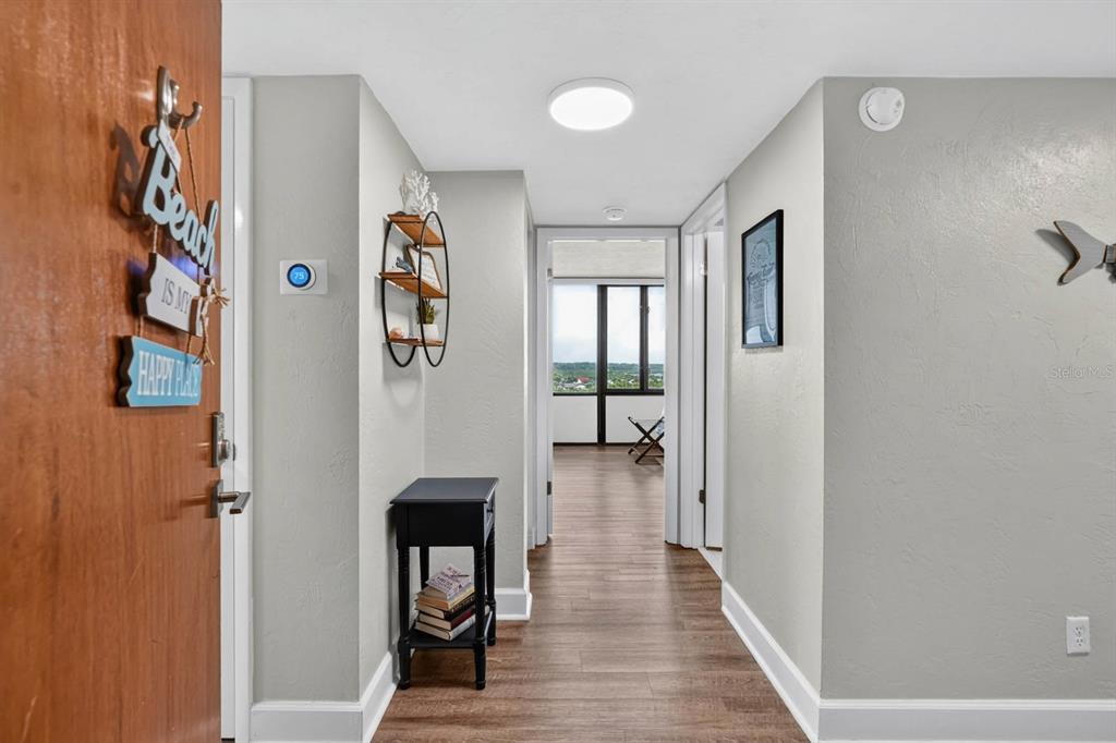 A hallway with wood-look flooring leads to a room with large windows and a view — 3580 S OCEAN SHORE BOULEVARD UNIT 509, FLAGLER BEACH, FL