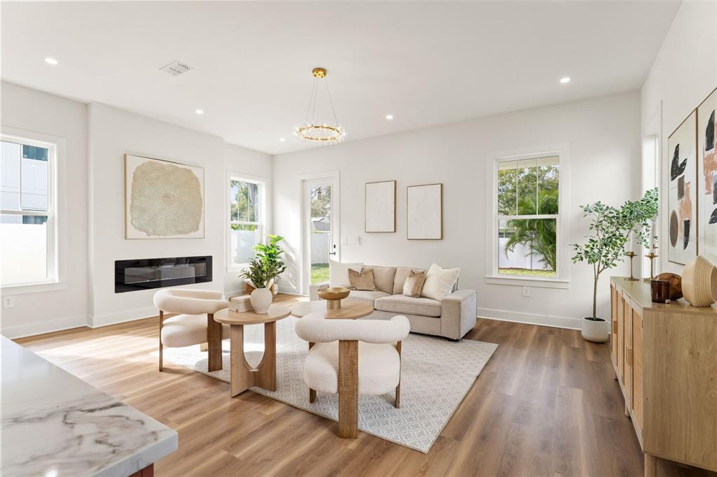 A modern living room features a fireplace, light wood flooring, a sofa, and two armchairs — 10164 HODSON PLACE, SEMINOLE, FL
