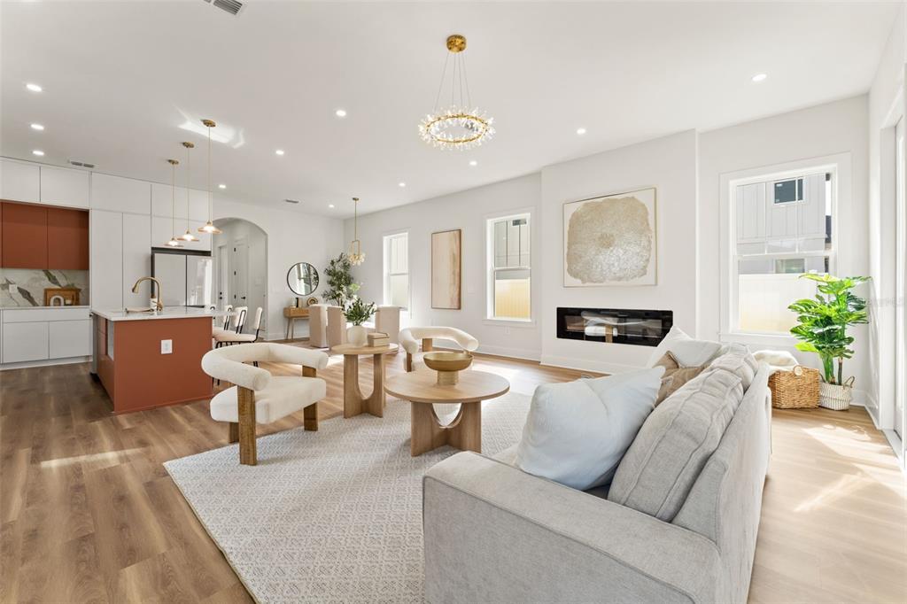 An open-concept living room and kitchen featuring light wood floors, white walls, and modern furniture — 10164 HODSON PLACE, SEMINOLE, FL