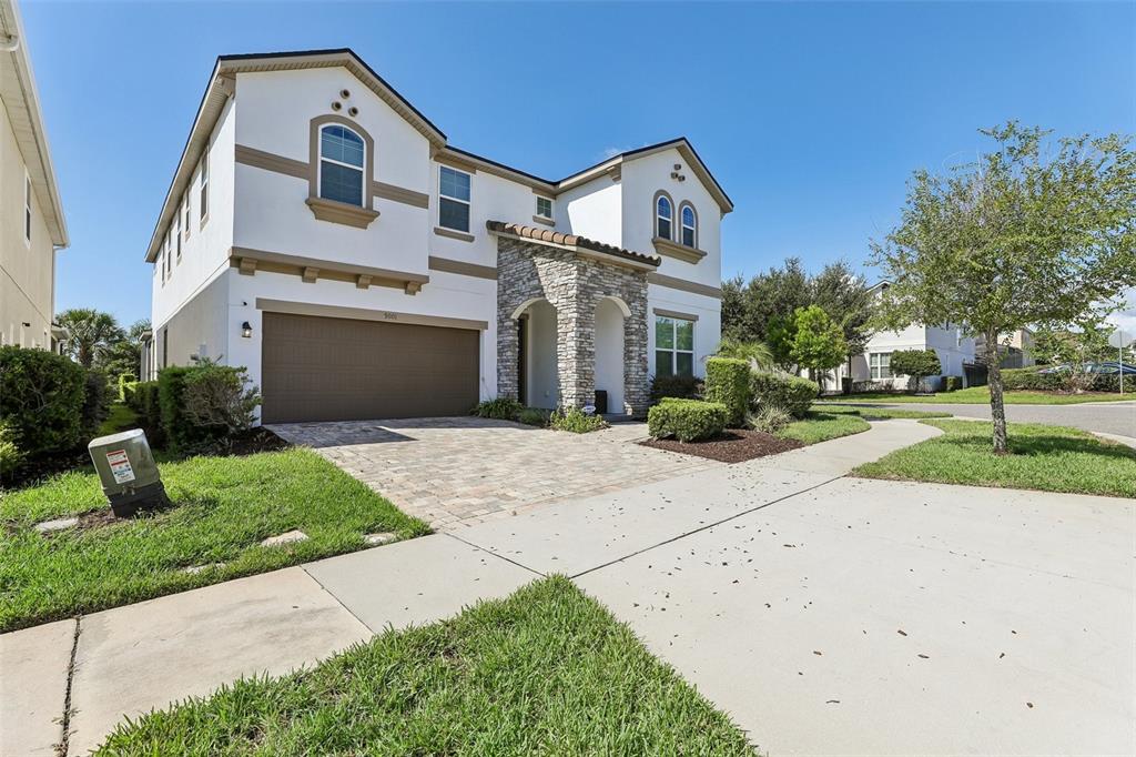 A two-story house with a stone-accented entryway, a paved driveway, and a two-car garage — 9001 SUNSHINE RIDGE LOOP, KISSIMMEE, FL