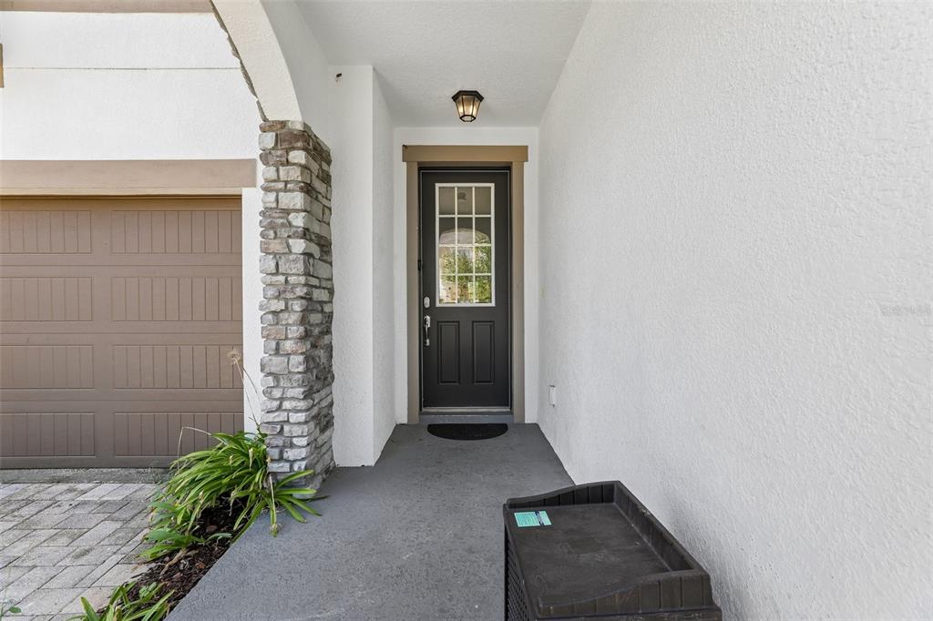 A front entryway features a dark door, a stone pillar, and a garage door — 9001 SUNSHINE RIDGE LOOP, KISSIMMEE, FL