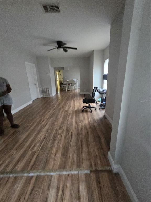 An open-concept living area features wood-look flooring, a ceiling fan, and a distant dining space — 421 1ST STREET, ORLANDO, FL