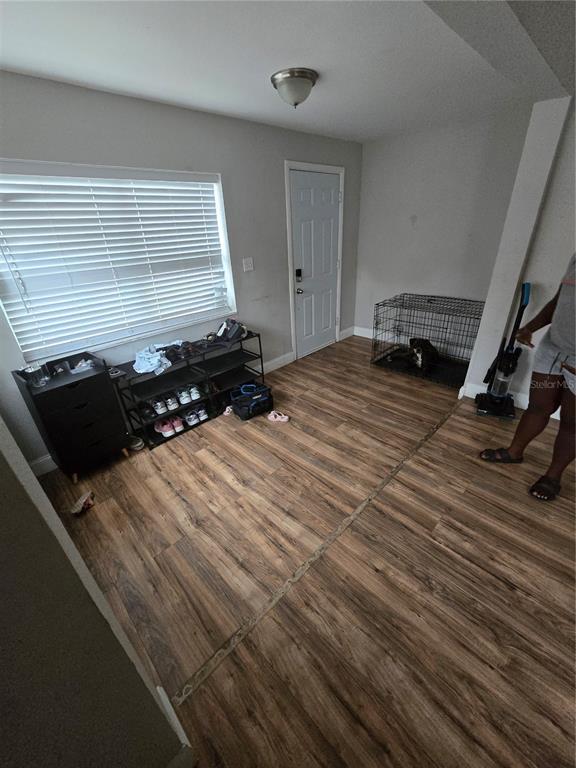 A room with wood-look flooring, a window with blinds, a storage rack, and a dog crate — 421 1ST STREET, ORLANDO, FL