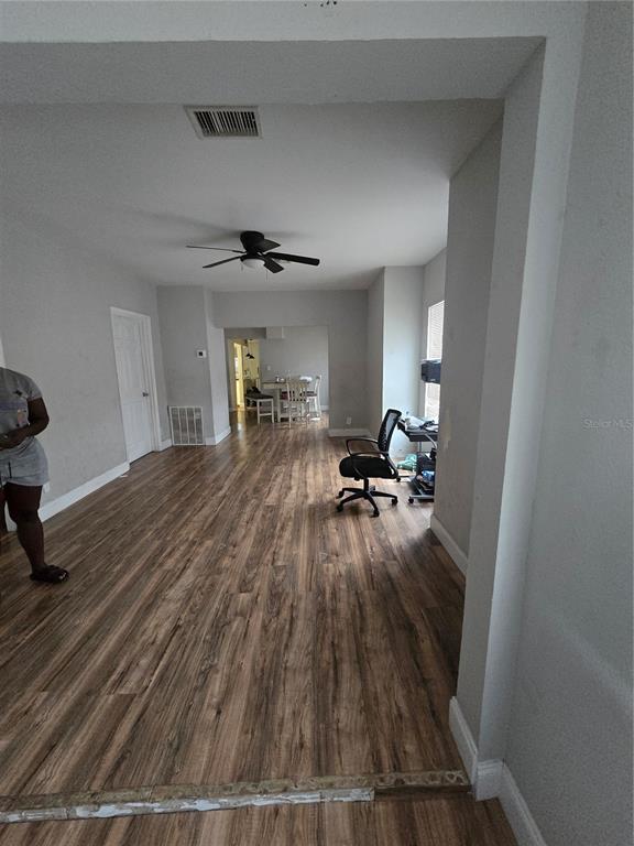 A living area with wood-look flooring leads to a dining space with a ceiling fan — 421 1ST STREET, ORLANDO, FL
