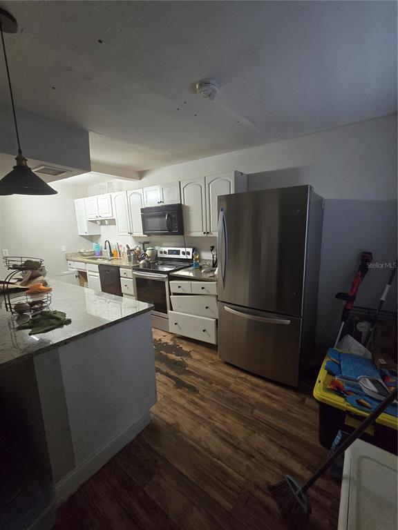 A kitchen features white cabinets, stainless steel appliances, a granite island, and wood-look flooring — 421 1ST STREET, ORLANDO, FL