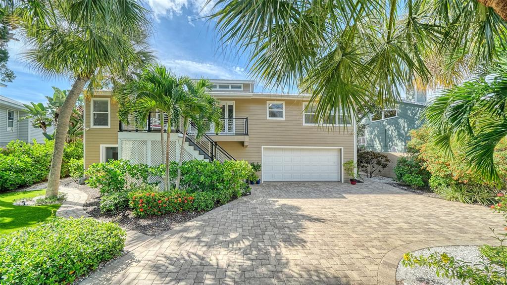 A two-story house with tan siding, a white garage door, and a paved driveway — 5188 SIESTA WOODS DRIVE, SARASOTA, FL