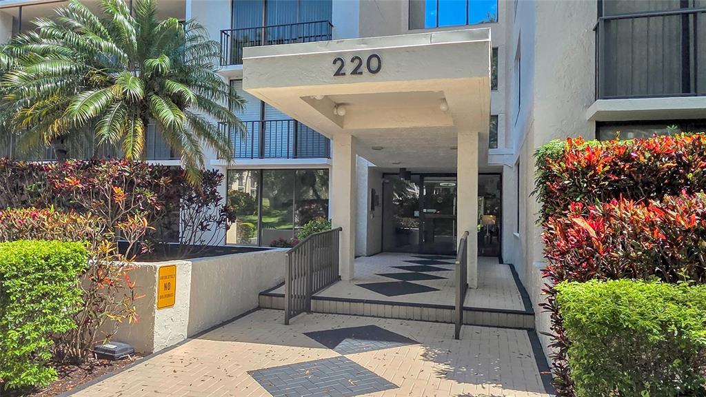 The exterior entrance of a multi-story building features a covered walkway with the number 220 — 220 BELLEVIEW BOULEVARD UNIT 812, BELLEAIR, FL