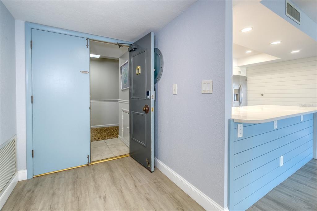 An open door leads to a hallway next to a kitchen with a blue island — 220 BELLEVIEW BOULEVARD UNIT 812, BELLEAIR, FL