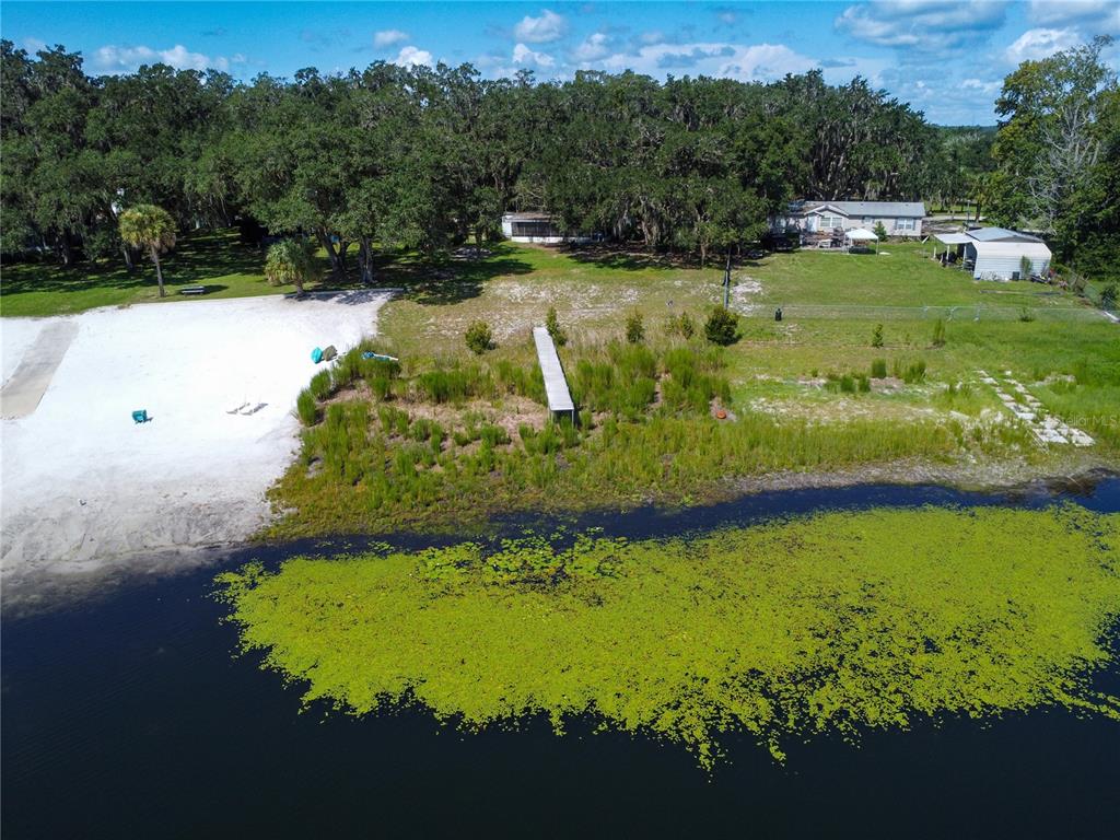 An aerial view shows a sandy beach, a wooden dock, and a house near a lake — 170 E COWPEN LAKE POINT ROAD, HAWTHORNE, FL