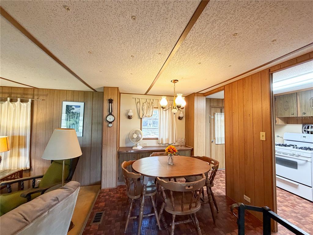 A dining area with a round wooden table, wood-paneled walls, and a patterned tile floor — 170 E COWPEN LAKE POINT ROAD, HAWTHORNE, FL