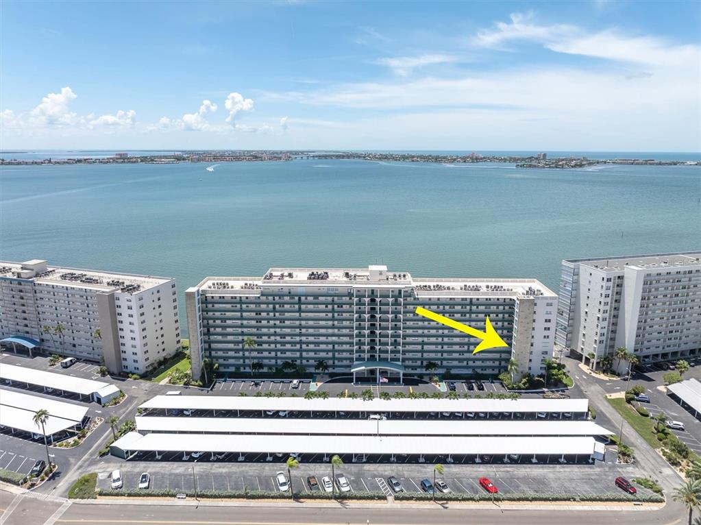 An aerial view shows a multi-story apartment building with a yellow arrow pointing toward it — 6020 SHORE BOULEVARD S UNIT 412, GULFPORT, FL