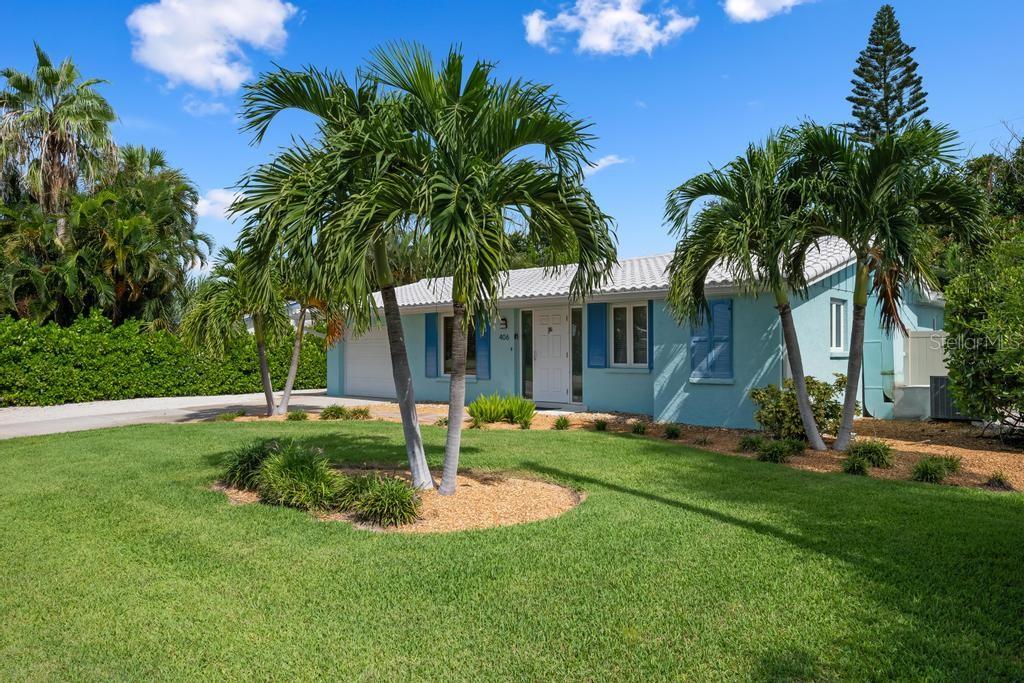 A light blue single-story house with a white roof and palm trees in the front yard — 406 BAY PALMS DRIVE, HOLMES BEACH, FL