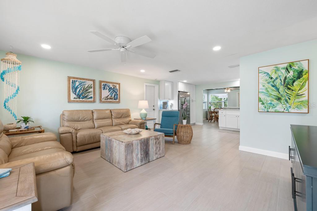 A living room features light-colored tile floors, a tan leather sofa, and a rustic wooden coffee table — 406 BAY PALMS DRIVE, HOLMES BEACH, FL