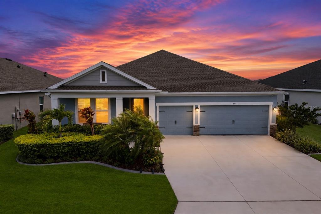 Two dark chairs sit on a stone patio overlooking a lake at sunset — 8611 MERCATOR COURT, PARRISH, FL