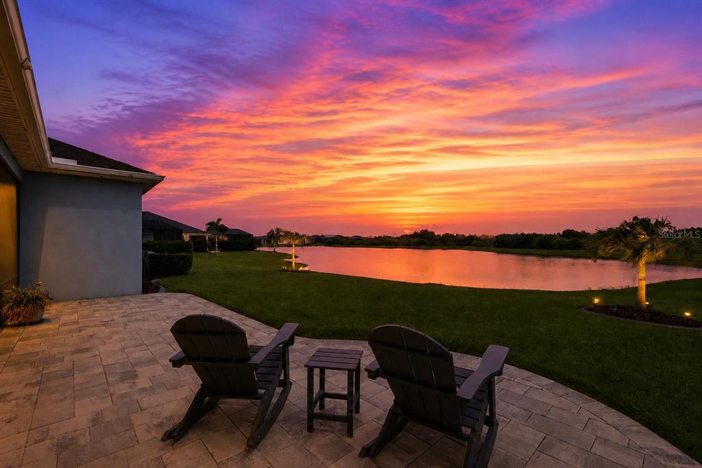 An aerial view shows a blue single-story house with a two-car garage and lakefront backyard — 8611 MERCATOR COURT, PARRISH, FL