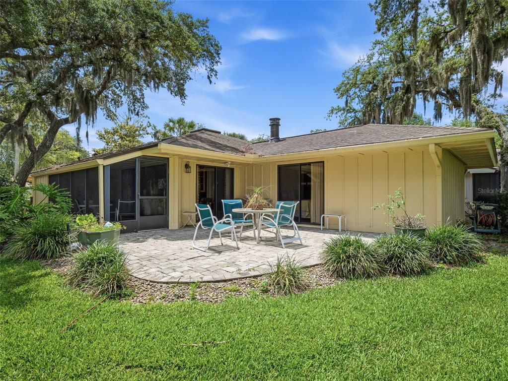 A kitchen features wood cabinets, stainless steel appliances, granite countertops, and a red area rug — 718 TANTALLON COURT, NEW SMYRNA BEACH, FL