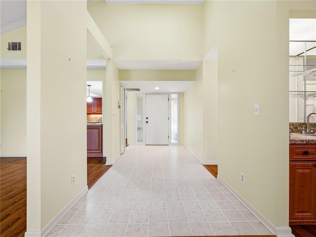 A dining room features a glass table, chandelier, wooden furniture, and large sliding glass doors — 718 TANTALLON COURT, NEW SMYRNA BEACH, FL
