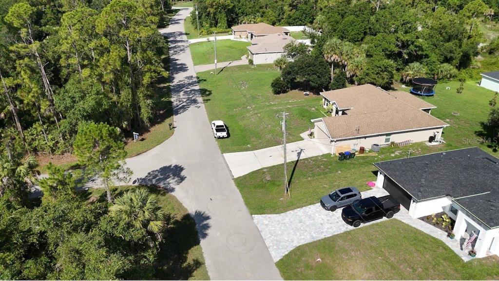 A paved path runs alongside a wooded area with dense trees and large palmetto plants — CARMELIA STREET, NORTH PORT, FL