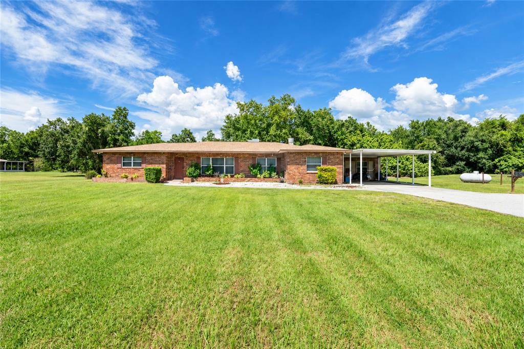 A single-story brick house with a carport sits on a large, grassy lawn — 24438 and 24450 HARBORVIEW ROAD, PORT CHARLOTTE, FL