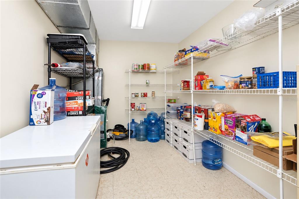 A pantry features wire shelving, a chest freezer, and several large water jugs on the floor — 24438 and 24450 HARBORVIEW ROAD, PORT CHARLOTTE, FL