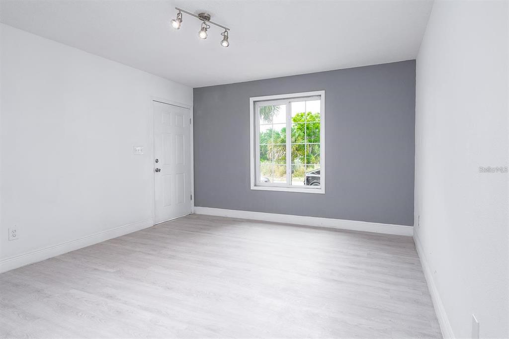 A room with white walls, a gray accent wall, a window, and light-colored flooring — 519 WILLIAMS STREET, MELBOURNE, FL