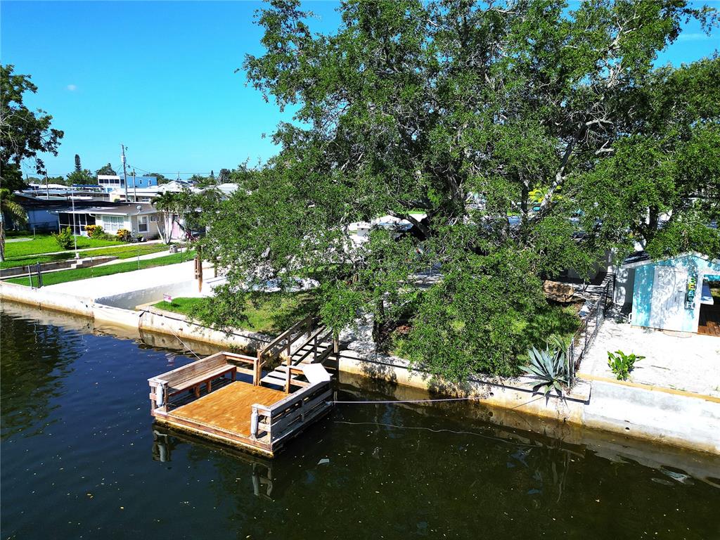 A house exterior features a textured stone facade, a wooden garage door, and a covered carport — 13400 CAROL DRIVE, HUDSON, FL