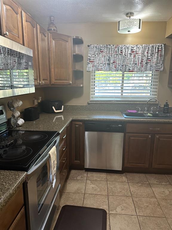 A kitchen features wood cabinets, stainless steel appliances, a tiled floor, and a window — 600 CRANES WAY UNIT 204, ALTAMONTE SPRINGS, FL
