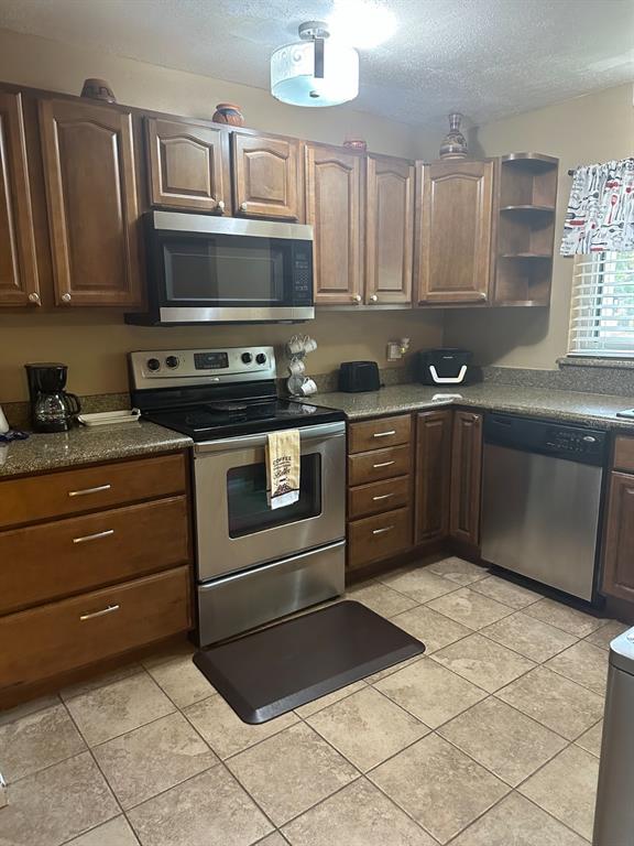 A kitchen features wood cabinets, stainless steel appliances, granite countertops, and tiled flooring — 600 CRANES WAY UNIT 204, ALTAMONTE SPRINGS, FL