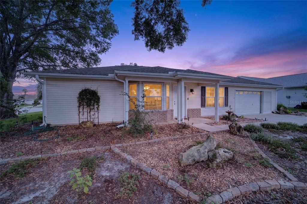 A single-story house with beige siding, a brick accent wall, and a landscaped front yard — 8661 SW 65TH TERRACE, OCALA, FL