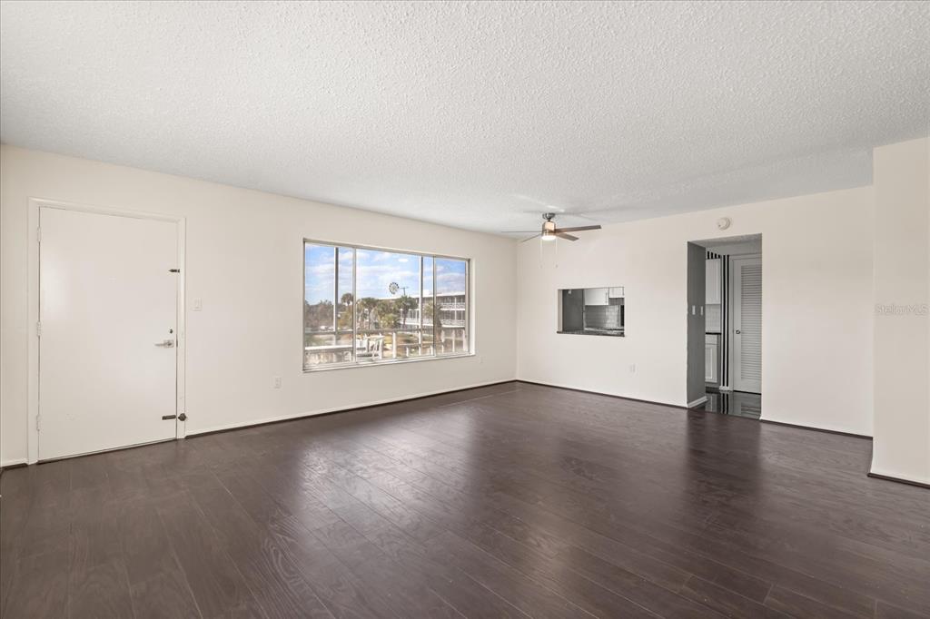 A galley kitchen features white cabinets, granite countertops, black-and-white striped wallpaper, and black tile flooring — 1700 6TH STREET NW UNIT B24, WINTER HAVEN, FL