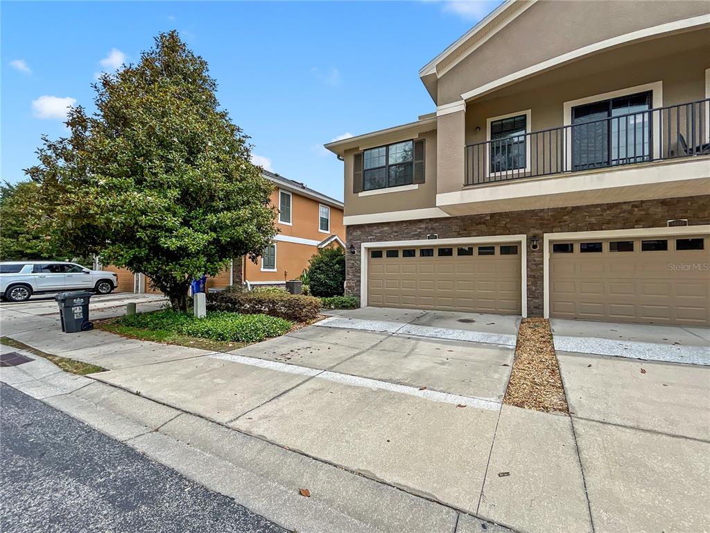 An exterior view of a two-story townhouse with a two-car garage and a balcony — 16615 KINGLETSIDE COURT, LITHIA, FL