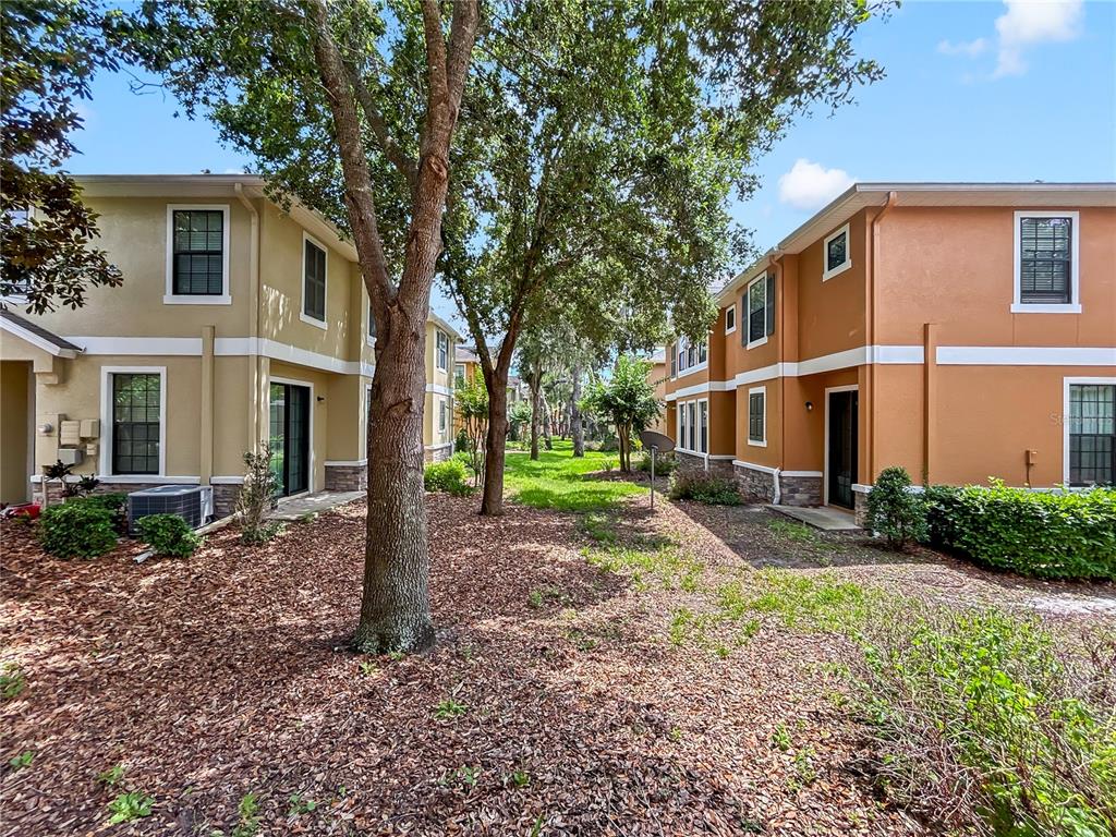 The exterior view shows two multi-story apartment buildings separated by a grassy courtyard with trees — 16615 KINGLETSIDE COURT, LITHIA, FL