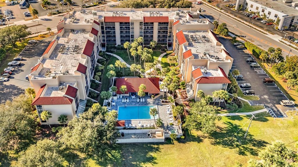 An aerial view shows a multi-story apartment complex with a central swimming pool and courtyard — 21405 OLEAN BOULEVARD UNIT 528, PORT CHARLOTTE, FL