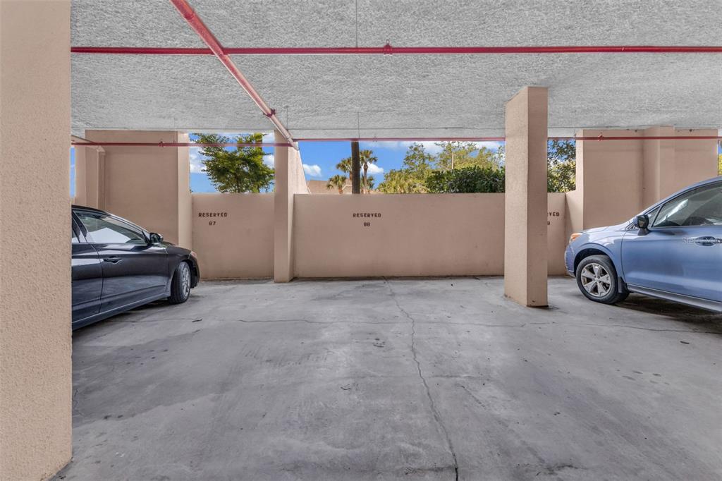 A covered parking area features concrete flooring and numbered reserved parking spaces — 21405 OLEAN BOULEVARD UNIT 528, PORT CHARLOTTE, FL